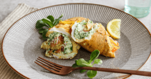 omelet wrap on a plate with fork and lemon wedge