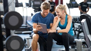 A man with a woman holding a tablet inside the gym