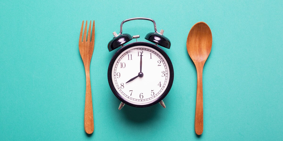 Clock with fork and spoon representing eating times for intermittent fasting